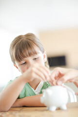 Girl filling piggy bank on counter