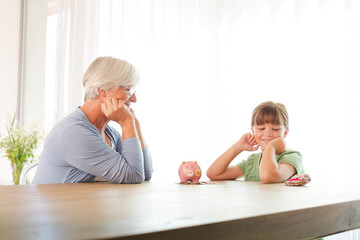 Older woman and granddaughter filling piggy bank