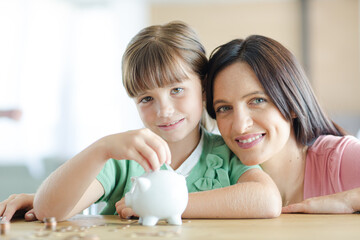 Mother and daughter filling piggy bank