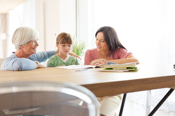 Mother  and grandmother helping girl with homework