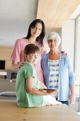 Three generations of women posing in kitchen, smiling