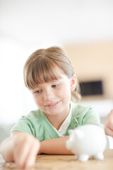 Girl filling piggy bank on counter
