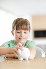 Girl filling piggy bank on counter