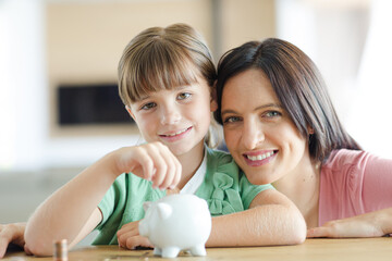 Mother and daughter filling piggy bank