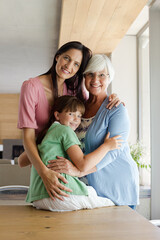 Three generations of women hugging in kitchen