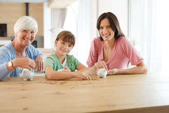 Three generations of women filling piggy bank