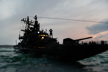 Silhouettes of a crowd standing at blurred military war ship on foggy background. Selective focus.