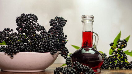 Elderberry medicinal herbs in a bottle, ripe black berries in a plate, squeezed elderberry juice....