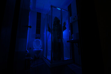 Fototapeta na wymiar Horror silhouette of woman in window. Scary halloween concept Blurred silhouette of witch in bathroom