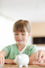 Girl filling piggy bank on counter