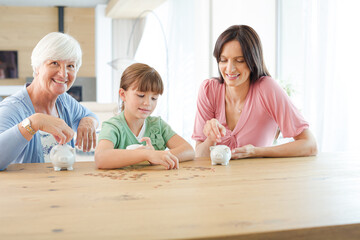 Three generations of women filling piggy bank