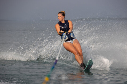 Woman making spray while waterskiing.