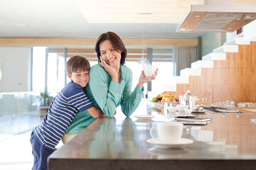 Son hugging mother in kitchen