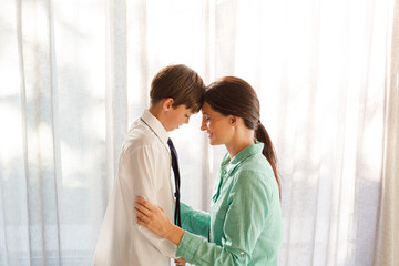 Fototapeta premium Mother and son touching foreheads at window
