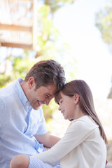 Father and daughter touching foreheads outdoors