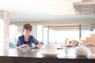 Boy using tablet computer in kitchen