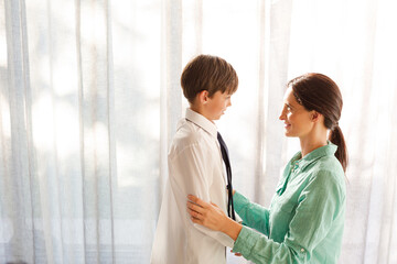 Fototapeta premium Mother and son touching foreheads at window