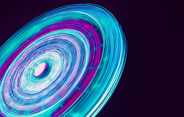 Amusement park carousel neon lights.Long exposure blue light spinning attraction. Blue and violet long exposure ferris wheel lights.
