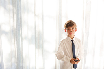 Fototapeta premium Boy in shirt and tie holding smartphone