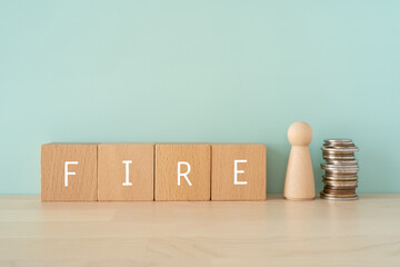 早期リタイア、FIRE｜「FIRE」と書かれた積み木と人形とお金 - obrazy, fototapety, plakaty