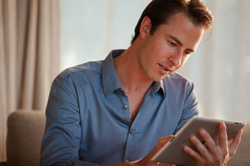 Man using tablet computer on sofa