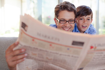 Father and son reading newspaper together