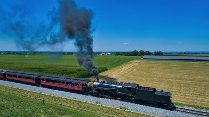 Obraz premium Aerial View of a Steam Locomotive Traveling Across a Fertile Farmland Landscape Blowing Smoke on a Beautiful Summer Day
