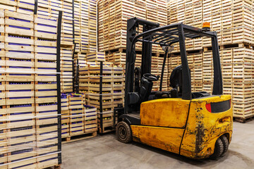 Forklift lifting crates with fruits. Cold storage interior.