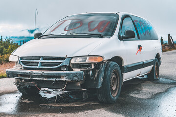 Fototapeta na wymiar abandoned junk car on parking lot in mountains on Alaska
