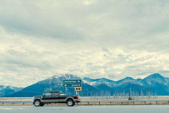 moving car on intersection on Alaska Highway driving by Anchorage Seward sign