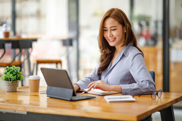 Obraz na płótnie Canvas Portrait of smiling beautiful business asian woman working in modern office desk using tablet laptop computer, Business people employee freelance online marketing e-commerce telemarketing concept.