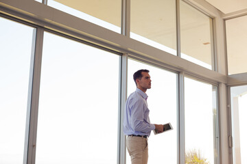 Businessman using tablet computer at window