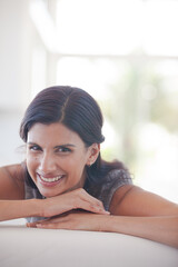 Woman resting chin in hands on sofa