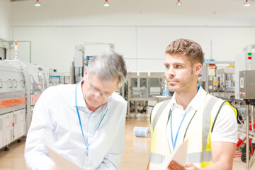 Fototapeta premium Supervisor and worker reading blueprints in factory