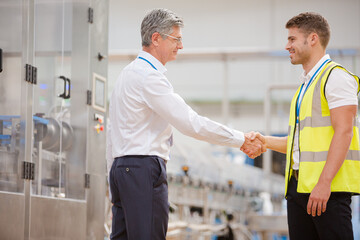 Supervisor and worker shaking hands in factory