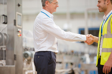 Supervisor and worker shaking hands in factory