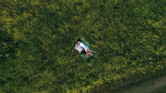 The romantic young couple laying on green grass