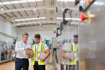 Supervisor and worker using digital tablet in factory