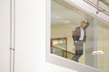 Supervisor leaning on glass window in warehouse