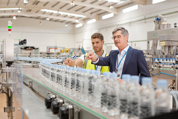 Supervisor and worker using digital tablet in factory