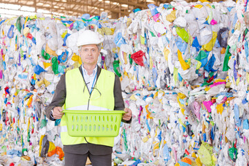 Worker standing by compacted recycling bundles