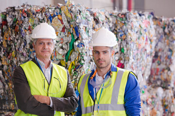 Workers standing by compacted recycling bundles