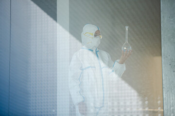 Fototapeta premium Scientist in clean suit examining liquid in test tube