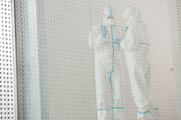 Scientists in clean suit with pipette and tray