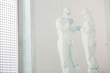 Scientists in clean suit with pipette and tray