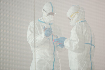 Scientists in clean suit with pipette and tray