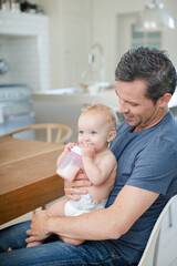 Obraz na płótnie Canvas Father feeding baby in kitchen