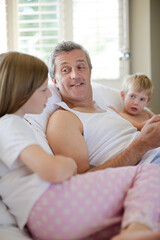 Obraz premium Father and children using digital tablet on bed