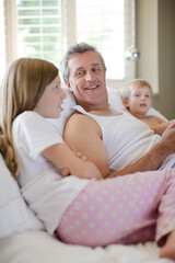 Fototapeta premium Father and children using digital tablet on bed
