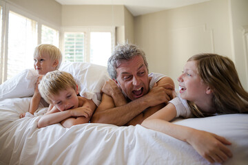 Obraz premium Father and children relaxing on bed